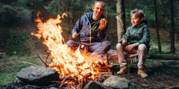 Father and son roast marshmallow on campfire
